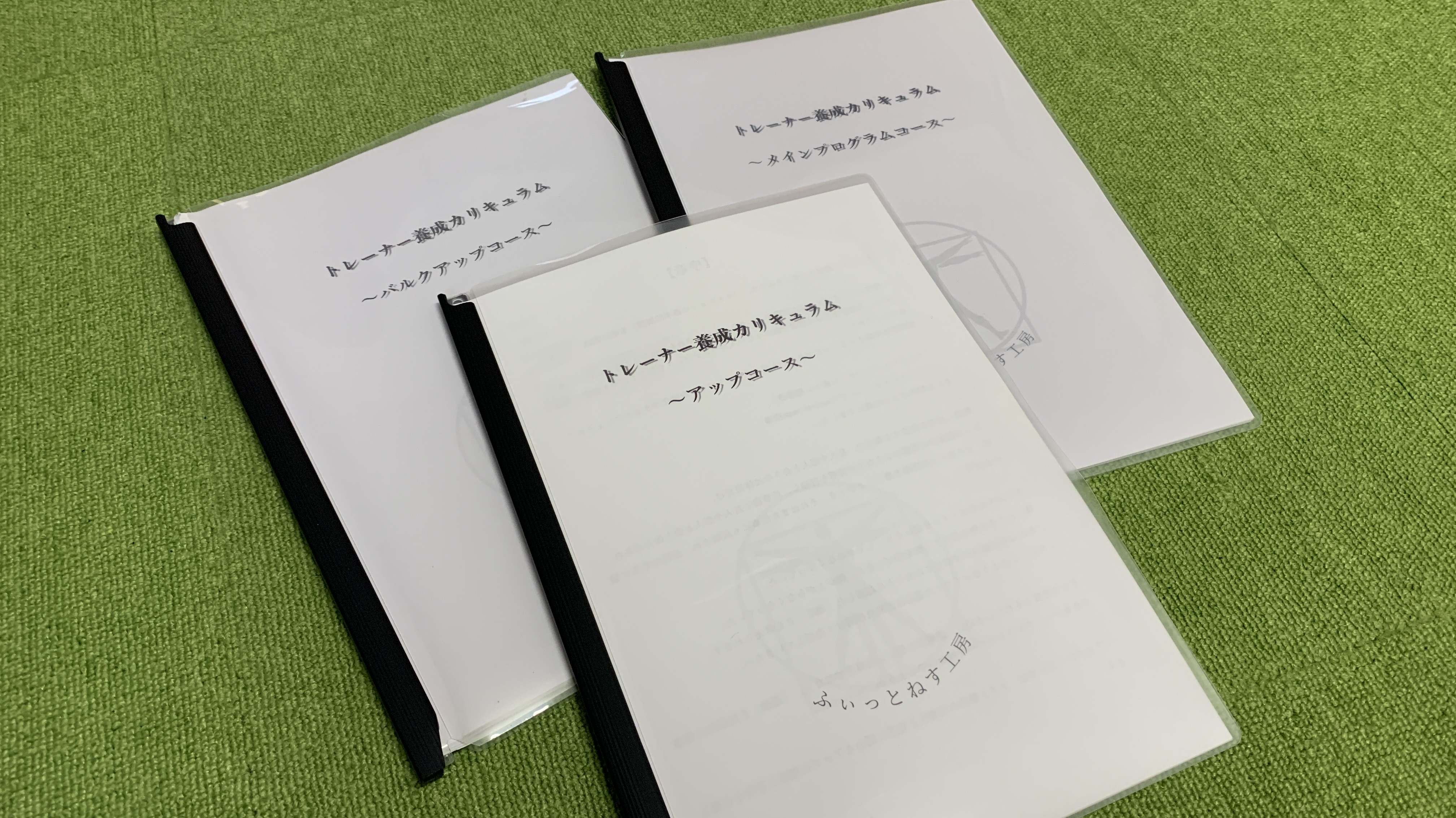 トレーナー養成講座で使用するテキストが3冊並んでいる写真。アップ、メイン、バルクアップの各コース教材を示す。